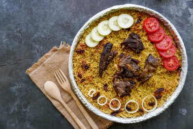 Geleneksel kebuli pilavı, aromatik baharatlı pirinç yemeği, taze et, kuru üzüm, salatalık, soğan, baharat ve taze domates dilimleri ile servis edilir.