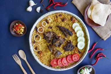 Geleneksel kebuli pilavı, aromatik baharatlı pirinç yemeği, taze et, kuru üzüm, salatalık, soğan, baharat ve taze domates dilimleri ile servis edilir.