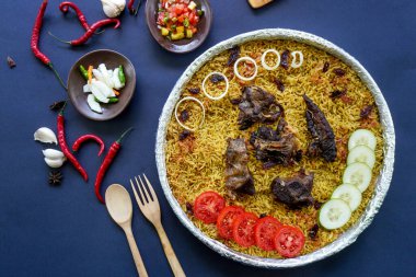 Geleneksel kebuli pilavı, aromatik baharatlı pirinç yemeği, taze et, kuru üzüm, salatalık, soğan, baharat ve taze domates dilimleri ile servis edilir.