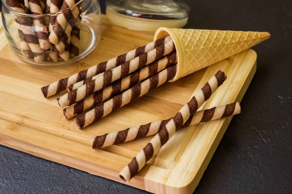 Waffle rolls. Sweet table with chocolate waffles, chocolate and ice cream on a black background