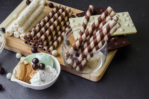 Waffle rolls. Sweet table with chocolate waffles, chocolate and ice cream on a black background