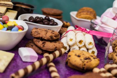 Çikolata ve bisküvi arka planda. Bir sürü çikolata, şeker, kurabiye, bisküvi, kek, çörek ve diğer tatlılar. Sütlü çikolata, koyu çikolata, waffle hindistan cevizi. Mor arkaplan