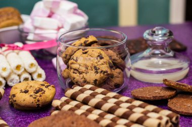 Çikolata ve bisküvi arka planda. Bir sürü çikolata, şeker, kurabiye, bisküvi, kek, çörek ve diğer tatlılar. Sütlü çikolata, koyu çikolata, waffle hindistan cevizi. Mor arkaplan