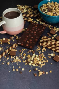 Çikolatalı tahıl gevreği, çikolatalı süt ve waffle rulosu, siyah arka planda mavi bir kasede.