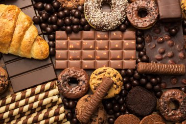 Çikolata dolgulu taze kruvasan ve kırsal arka planda çeşitli çikolatalar ve kurabiyeler.