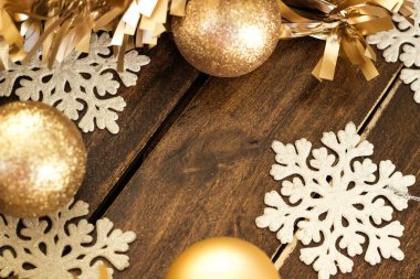 Altın süslemeli altın Noel topları ve ahşap arka planda kar taneleri