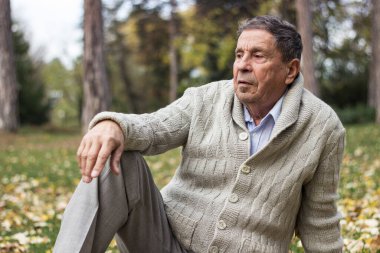 Kıdemli adam düşünceli bir şekilde parkta oturuyor.