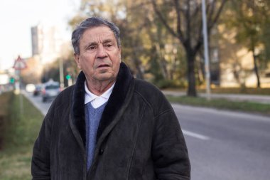 Düşünceli kıdemli adam caddeyi geçiyor.