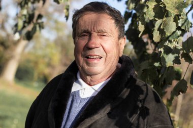 Gülümseyen ve tatmin olmuş yaşlı bir adam parkta yürüyor.