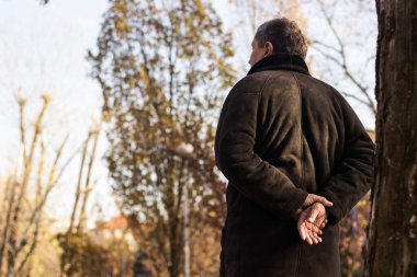 Parkta yürüyen dalgın kıdemli adam.