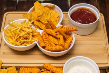 Kesme tahtasında tortilla cipsi ve sos.