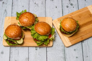 Ahşap masada servis edilen taze ızgara burgerler.