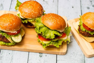 Ahşap masada servis edilen taze ızgara burgerler.