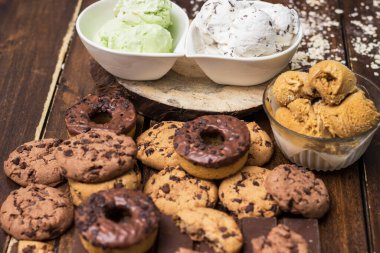 İçinde dondurma, çörek ve çikolata parçacıklı kurabiyeler olan tatlı bir masa.