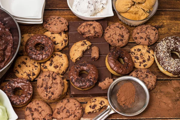 A sweet table containing ice cream, donuts and chocolate chip cookies