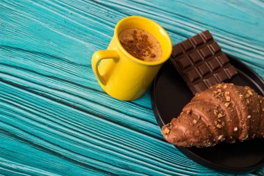 Coffee break with chocolate pastry. Cup of cappuccino coffee with croissant. Coffee and croissant on table