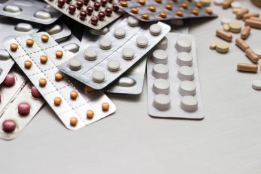 Variation of vitamins and pills on a green leaf on a white background