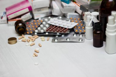 Variation of vitamins and pills on a green leaf on a white background