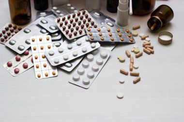 Variation of vitamins and pills on a green leaf on a white background