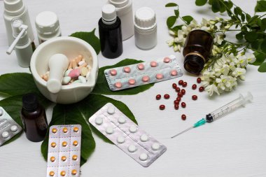 Variation of vitamins and pills on a green leaf on a white background