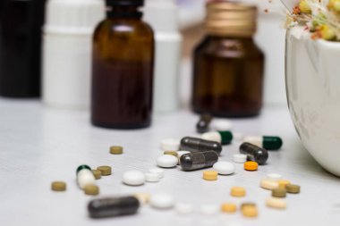 Variation of vitamins and pills on a green leaf on a white background