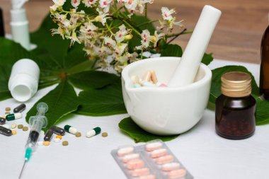 Variation of vitamins and pills on a green leaf on a white background