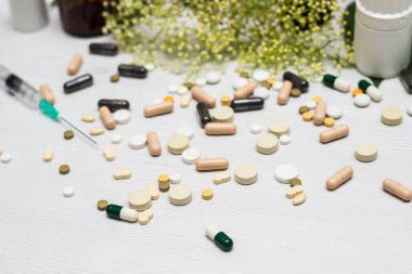 Variation of vitamins and pills on a green leaf on a white background