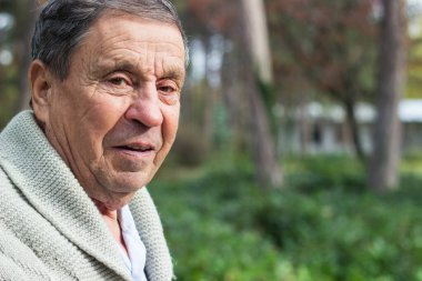 Senior man looking at camera, joyful. Walking in the park