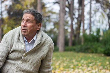 Senior man sitting on a grass alone. Around of a nature