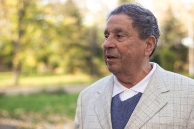 Older man with wrinkled and serious face, outdoor walking