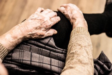Grandmother's hands on the knee, sitting on the couch