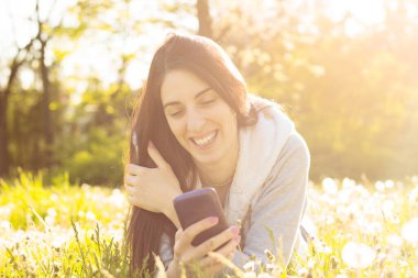 Woman enjoying the sun outdoors in sunset, talking on the smartphone