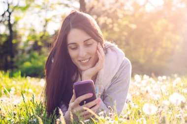 Woman enjoying the sun outdoors in sunset, talking on the smartphone