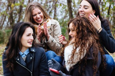 Akıllı telefonlu bir grup arkadaş, konuşup gülüyorlar.