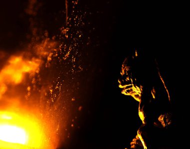 O korkunç heykel alevli ateşin kenarında yatar..