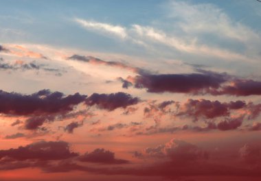 Gökyüzünde pembe ve gri bulutların yer aldığı güzel bir gün batımının geniş bir görüntüsü..