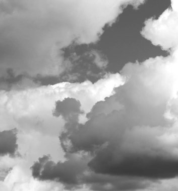 Gökyüzü yoğun, dönen gri bulutlarla dolu, yaklaşan fırtınayı işaret ediyor. Dinamik oluşumlar atmosferik ve dengesiz bir zemin oluşturur..