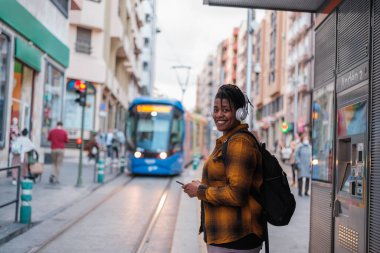 Tramvayı beklerken müzik dinleyen genç bir adam. Kavram: Toplu taşıma, yaşam tarzı, açık hava