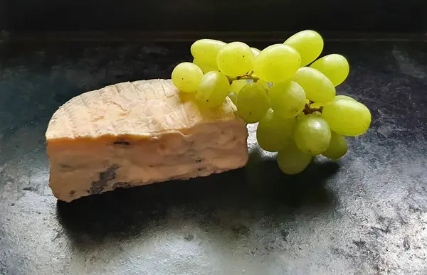 Siyah arkaplanda mavi peynir ve yeşil üzüm