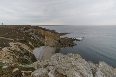 Sahilde kayalık uçurumlar, Cap de la Chevre 'nin yanında güzel fundalarla kaplı bir kumsal Crozon, Brittany, Fransa