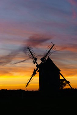 Günbatımından sonra canlı ve dramatik bir gökyüzü geleneksel yel değirmeni silueti Moulins de Trouguer, Cleden-Cap-Sizun, Brittany, Fransa