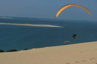 Güneşli bir günde, Pilat kumulunda rüzgarlı havada uçan tek bir paraglider, Arcachon, Yeni Aquitaine, Fransa