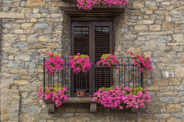 stock image Old stone house with beautiful flowers at the window in the medieval village of Ainsa in the pyrenees, Aragon, Spain