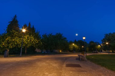 Gecenin mavi saatinde, Pamplona, Navarra, İspanya 'da gökyüzünde ay olan kaledeki boş park bankında.