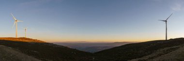 Serra da Arada 'daki rüzgar türbinlerinin panoraması altın akşam güneşinde gün batımında, Sao Pedro do Sul, Portekiz