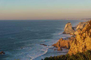 Atlantik Okyanusu kıyısında gün batımında altın ışıklı kayalar batıda, Cape Roca, Cabo da Roca, Portekiz.