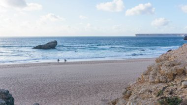 Praia do Tonel plajında iki sörfçü denize doğru yürüyordu, Sagres, Algarve, Portekiz