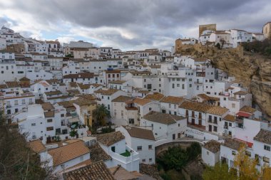 View over typical andalusian village with white houses and street with dwellings built into rock overhangs, Setenil de las Bodegas, Andalusia, Spain clipart