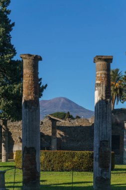 Garden inside ancient luxury house Casa del Fauno in the ruins of Pompei with view through columns at volcano Mount Vesuvius, Pompeii, Campania, Italy clipart