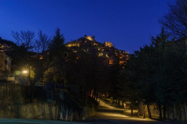 Morano Calabro 'nun alacakaranlıkta sarı sokak ışıklarıyla mavi saat boyunca gece görüşü. Cosenza ili, Calabria, İtalya